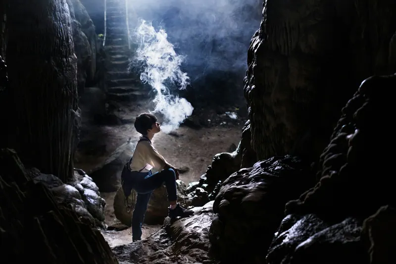 A traveller resting on rocks inside a dark limestone cave