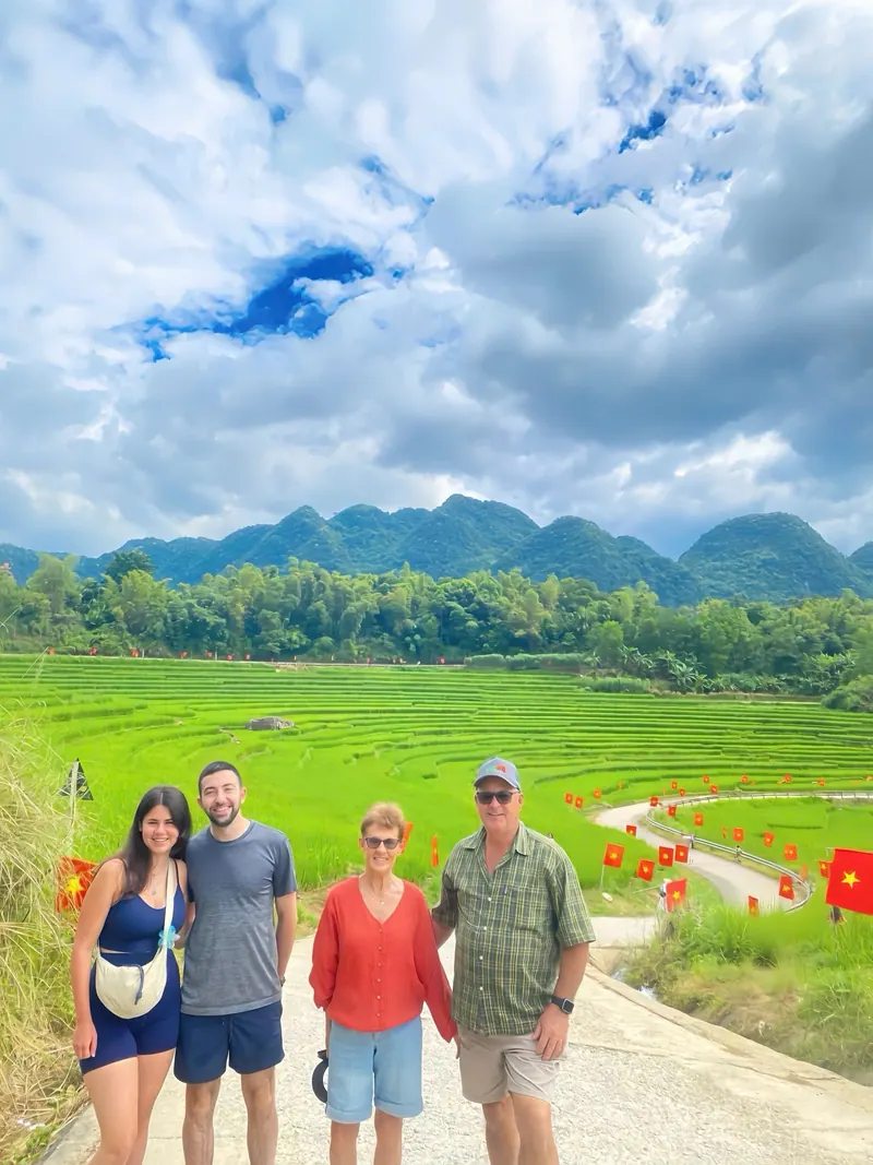 Four travellers in front of green rice fields and limestone mountains in Pu Luong