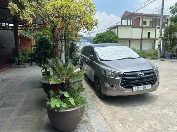 A silver 7-seat Toyota Innova parked by a garden