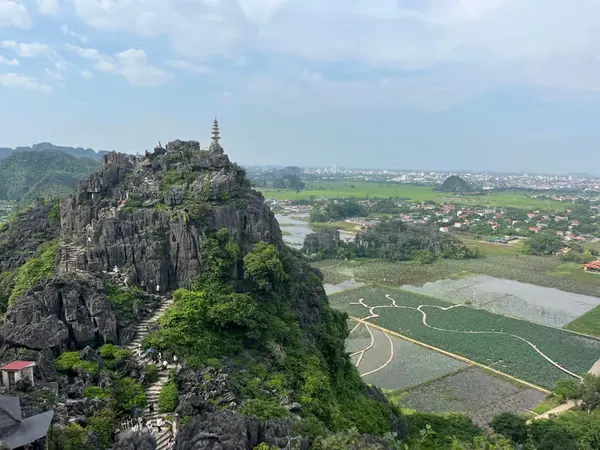 A pagoda tower on a karst peak above the rice fields and river valley, Ninh Binh